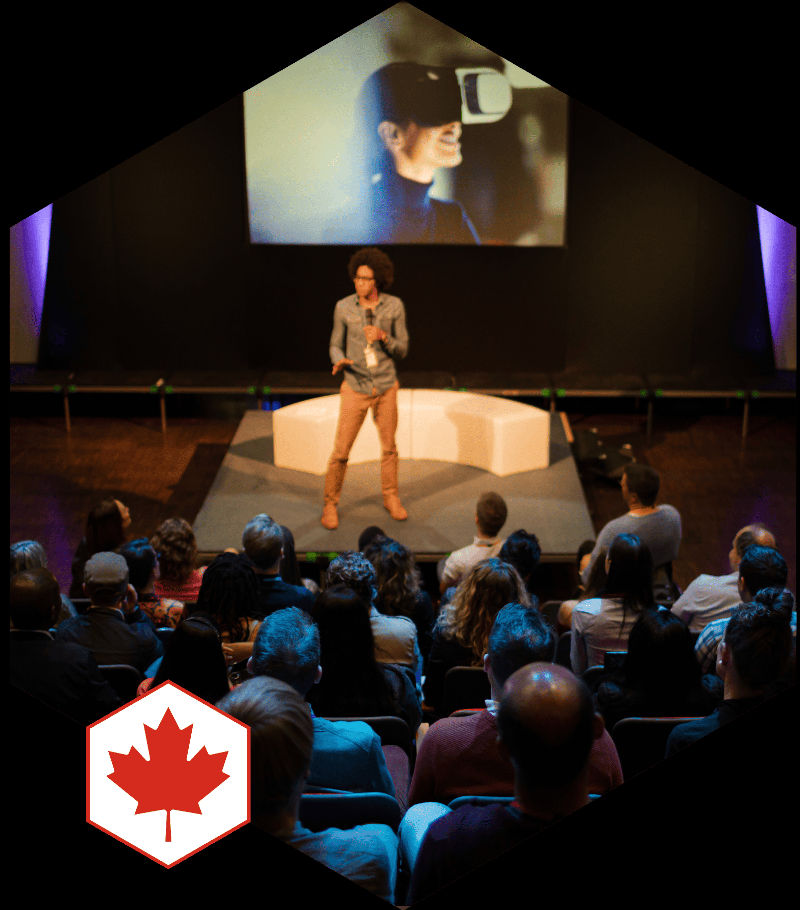 A speaker on a stage presents to an audience.